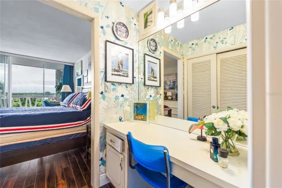 Bright bedroom with floral wallpaper, vanity table, and fresh flowers.